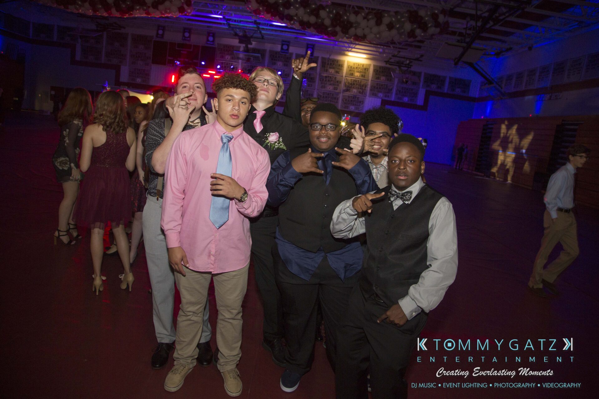 A group of young people pose for a photo in a dimly lit gymnasium during a celebration.