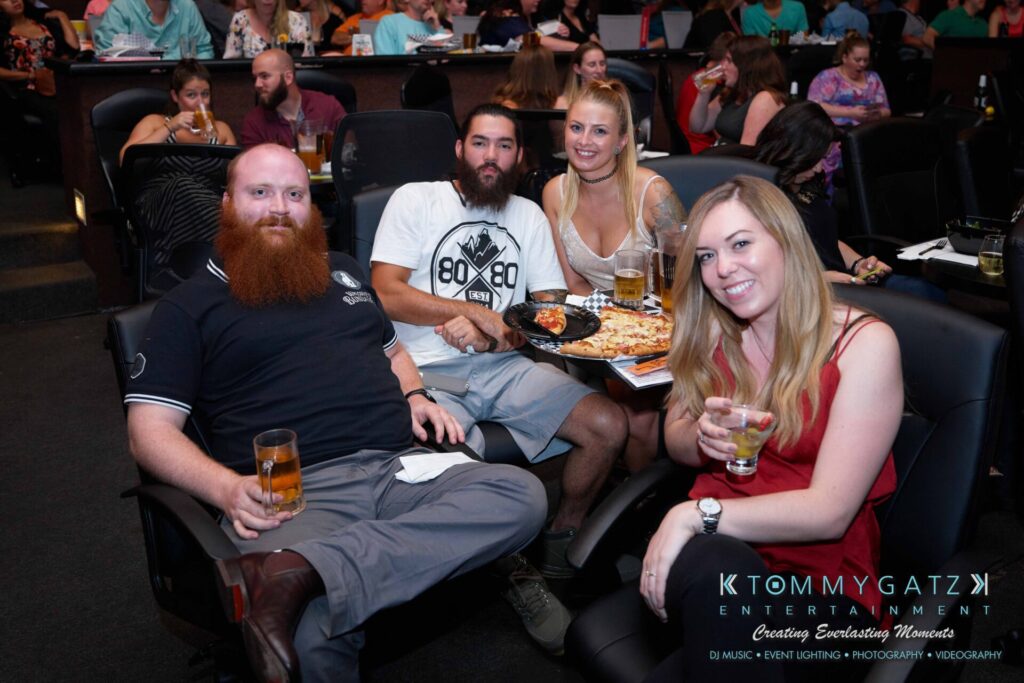 Four people seated at a table, enjoying drinks and food in a lively venue.
