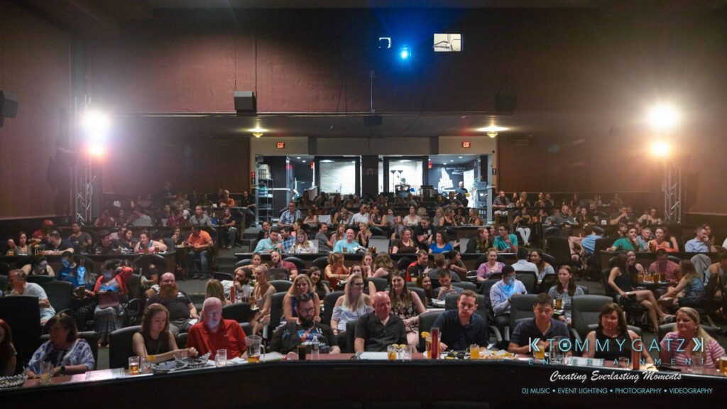 Audience seated in a theater-style venue, facing the stage.