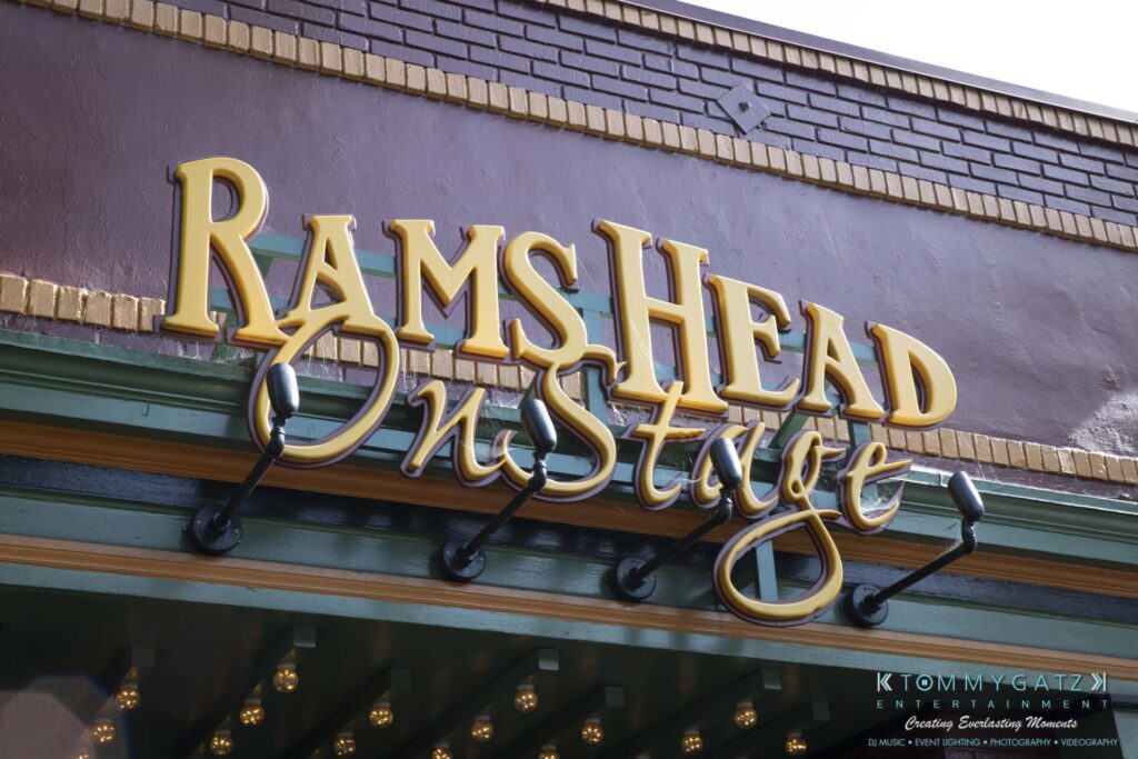Sign for "Rams Head On Stage" with decorative gold letters against a purple and green background.