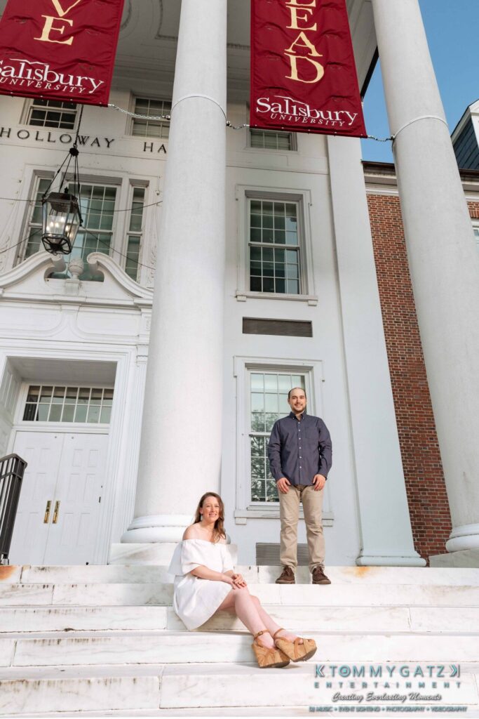 Two people are standing on the steps in front of a building with large columns and banners that read "Salisbury University" and "EAB.