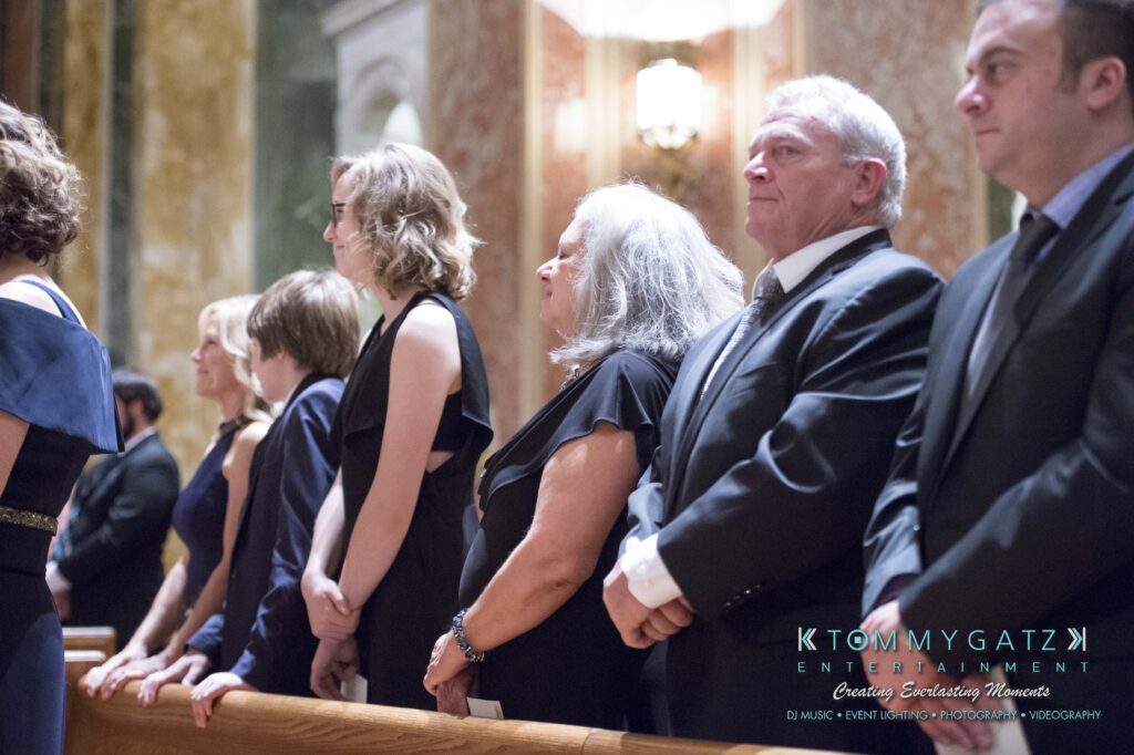 People standing in a row at an indoor event, wearing formal attire.