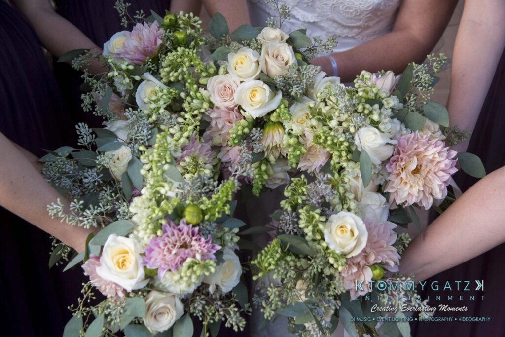 Close-up of people holding bouquets of white and pink flowers with greenery.