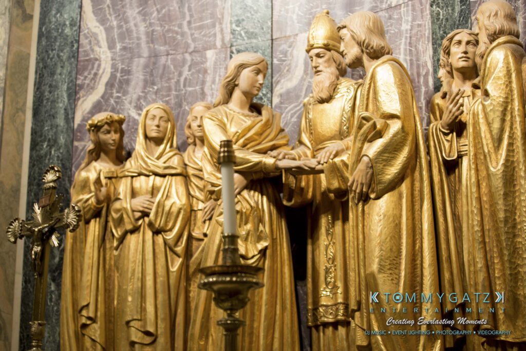 A close-up of a golden religious statue depicting figures in traditional attire engaged in a ceremonial scene.