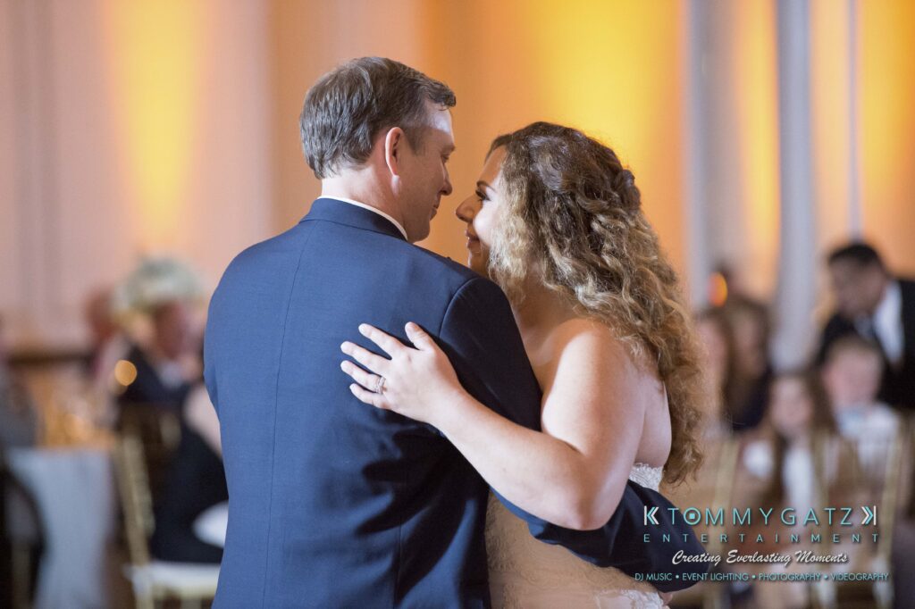 A bride and groom share a dance at a wedding reception surrounded by guests, with the text "Tommy Gatz Entertainment" in the corner.