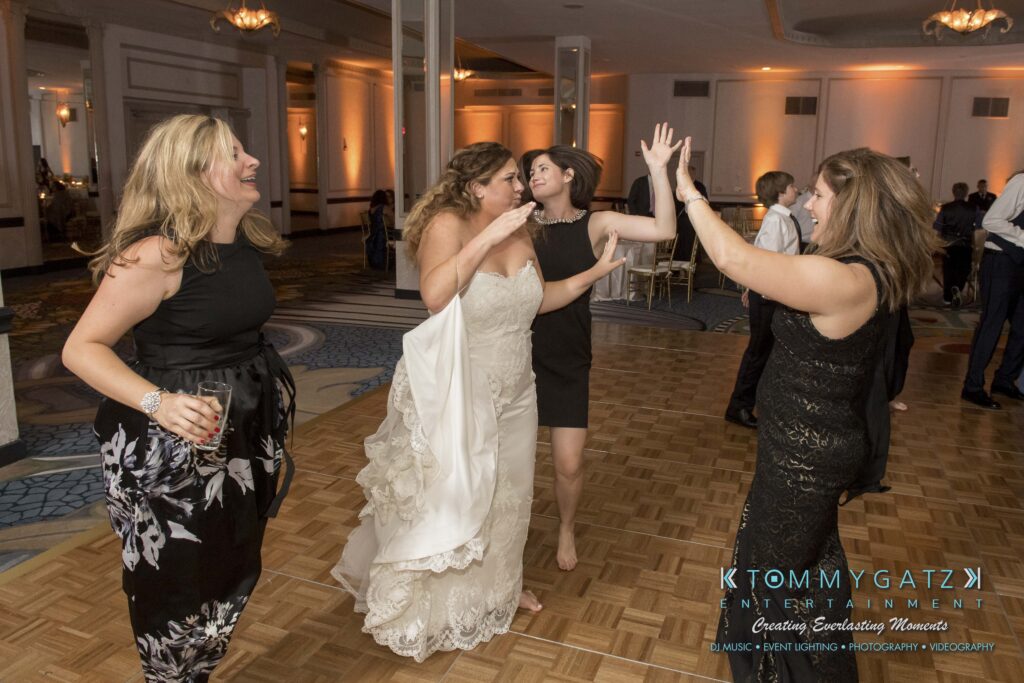 Women dancing together on a wooden dance floor in a large, elegantly decorated room.