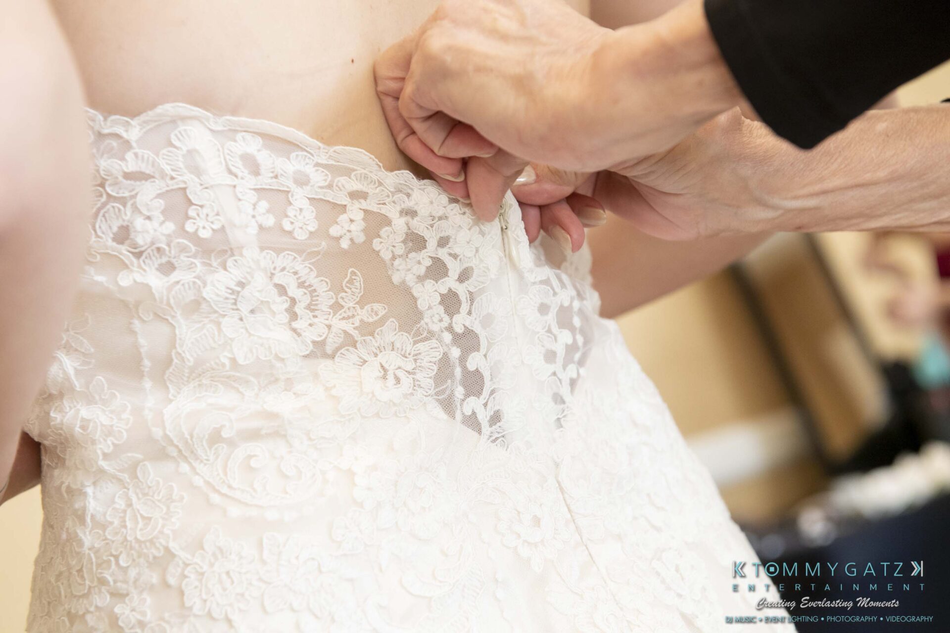 Hands fastening a lace wedding gown on a bride.