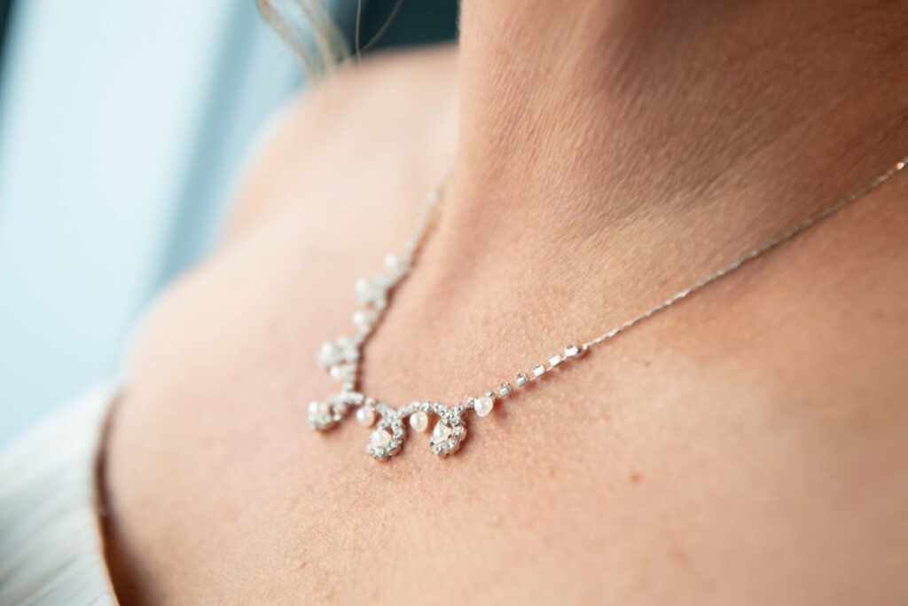 Close-up of a silver necklace with dangling pearls worn by a person.