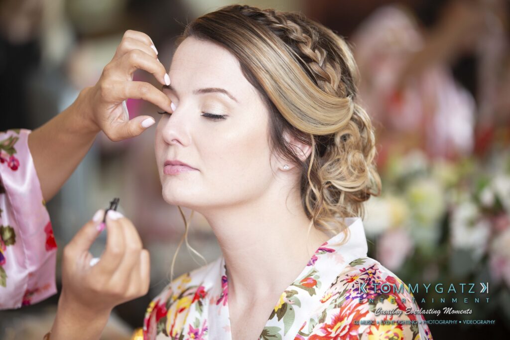 Person with braided hair having makeup applied, wearing a floral robe.