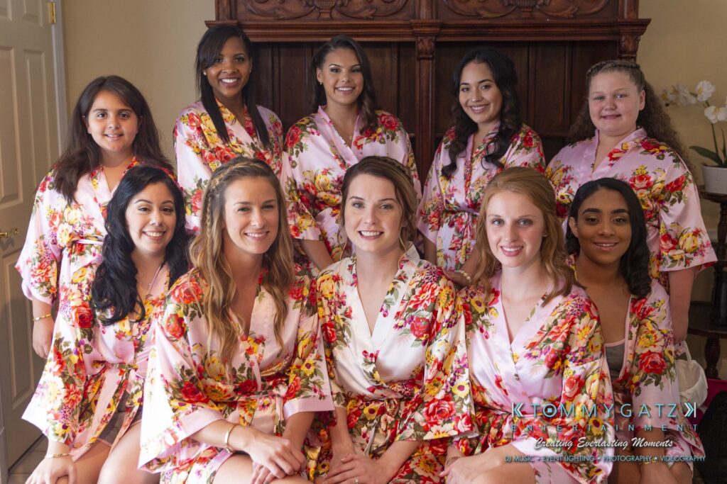 A group of eleven women wearing matching floral robes, posing indoors.