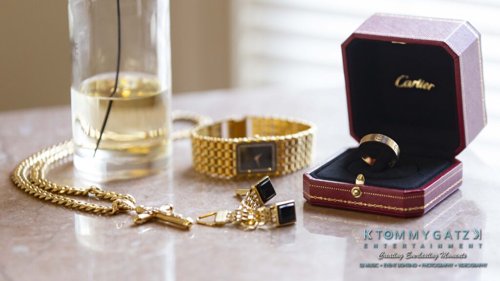 Gold jewelry items including a necklace, watch, cufflinks, and two rings in a Cartier box are displayed on a table.