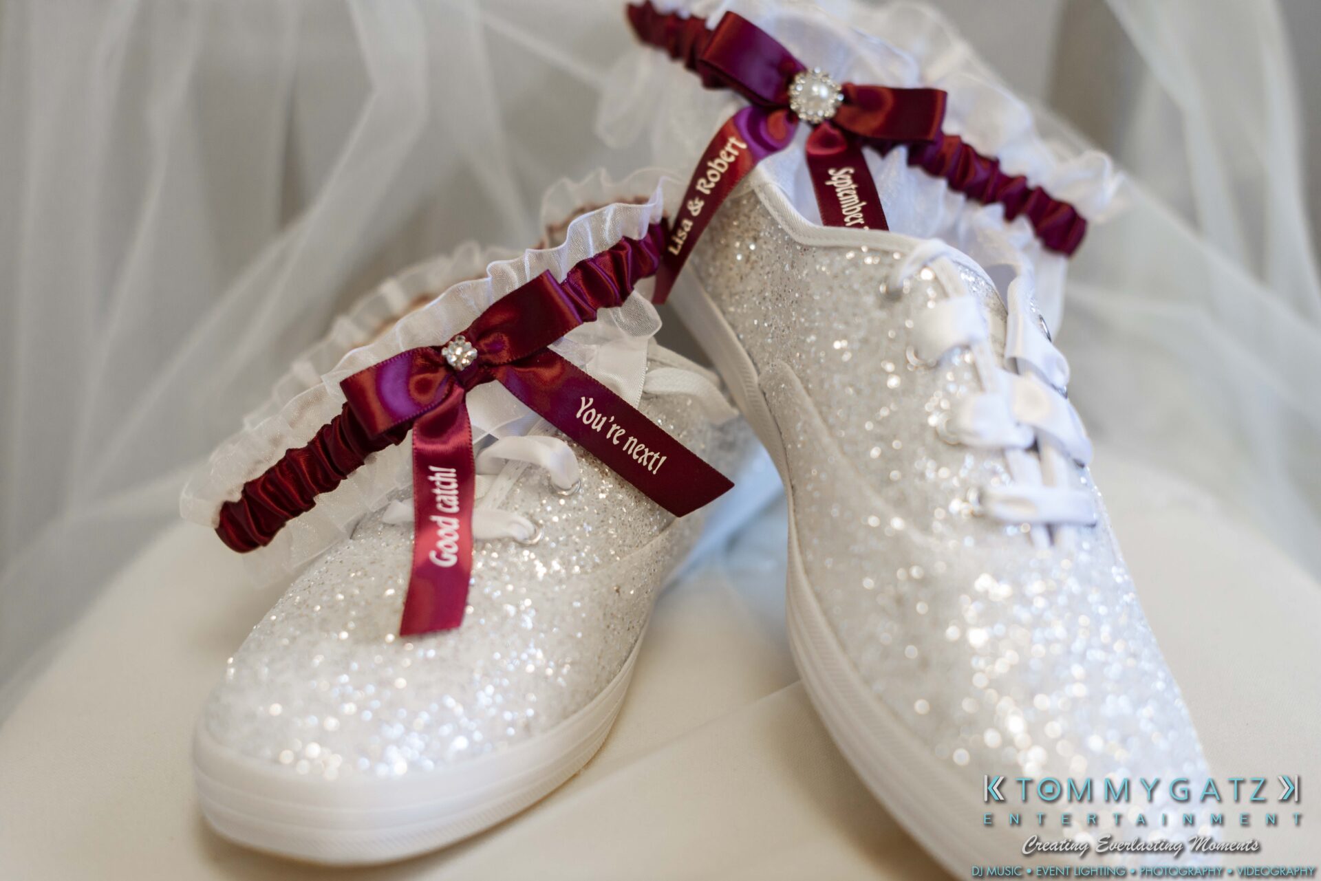 Sparkly white sneakers with lace-up ribbons are adorned with red garters.