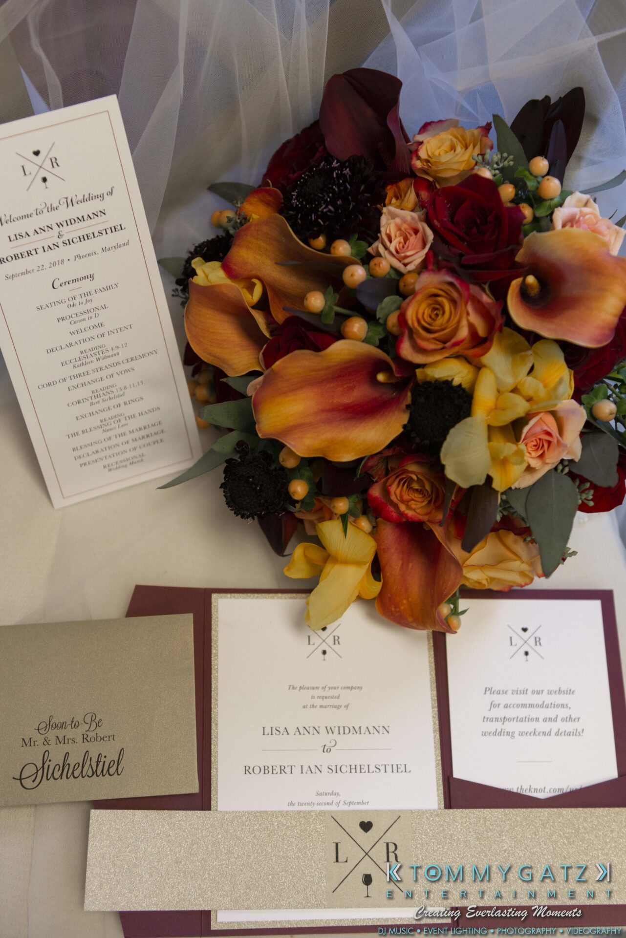 Wedding invitation suite with floral arrangement in red, yellow, and orange. Includes a program, invitation, and RSVP card with gold details.