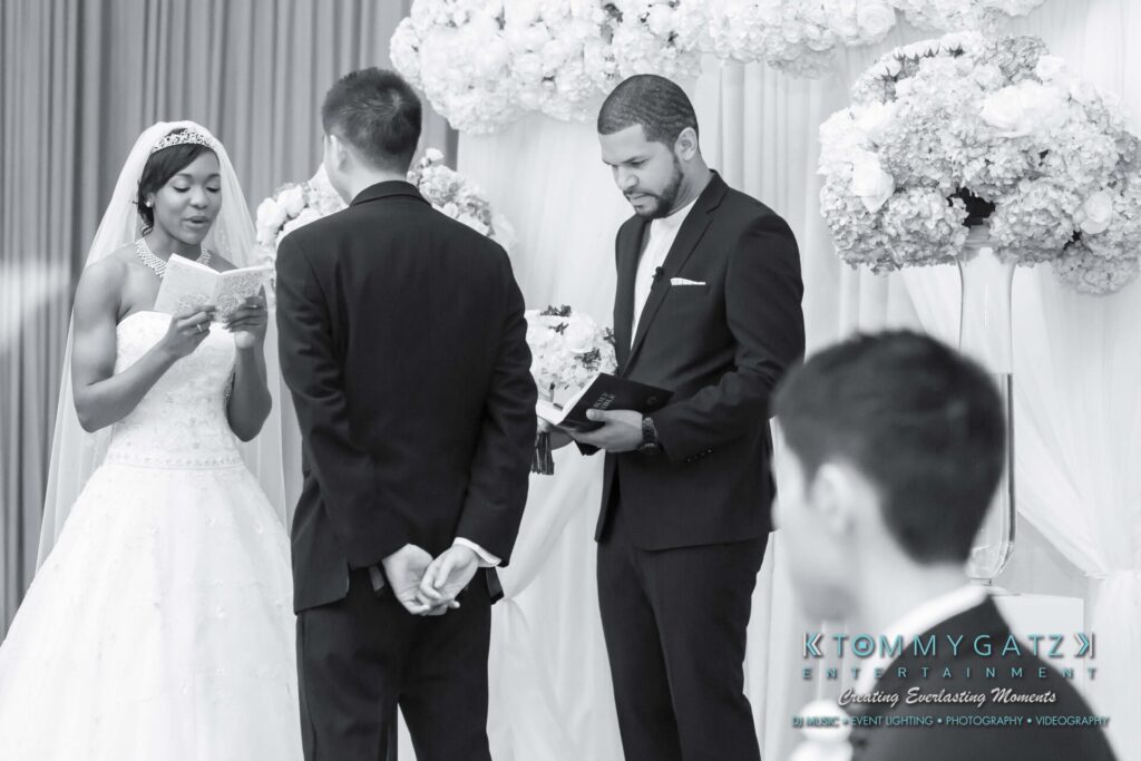 A bride and groom stand at the altar during a wedding ceremony, with another man holding a book nearby.