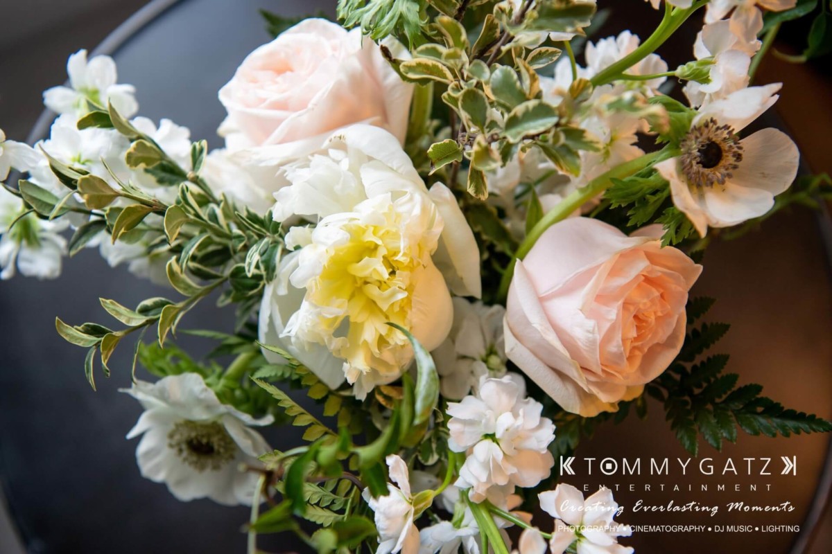 Bouquet of pale pink roses, white peonies, and greenery on a dark background.