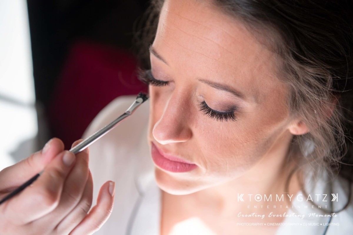 A woman has eyeshadow applied with a brush.