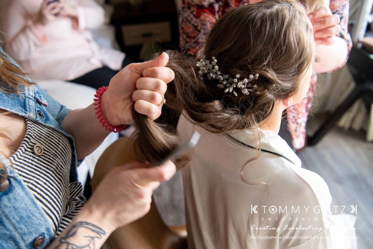 A person styles another's hair, using a comb and hairpin with floral details, while seated indoors.