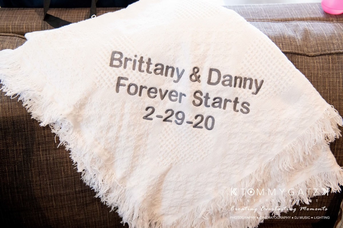 White blanket with the text "Brittany & Danny Forever Starts 2-29-20" embroidered in black.