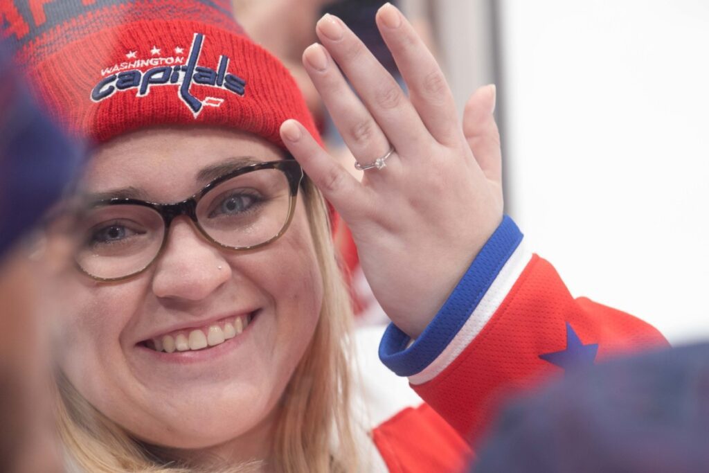 A person wearing a Washington Capitals beanie smiles and shows a ring on their finger.