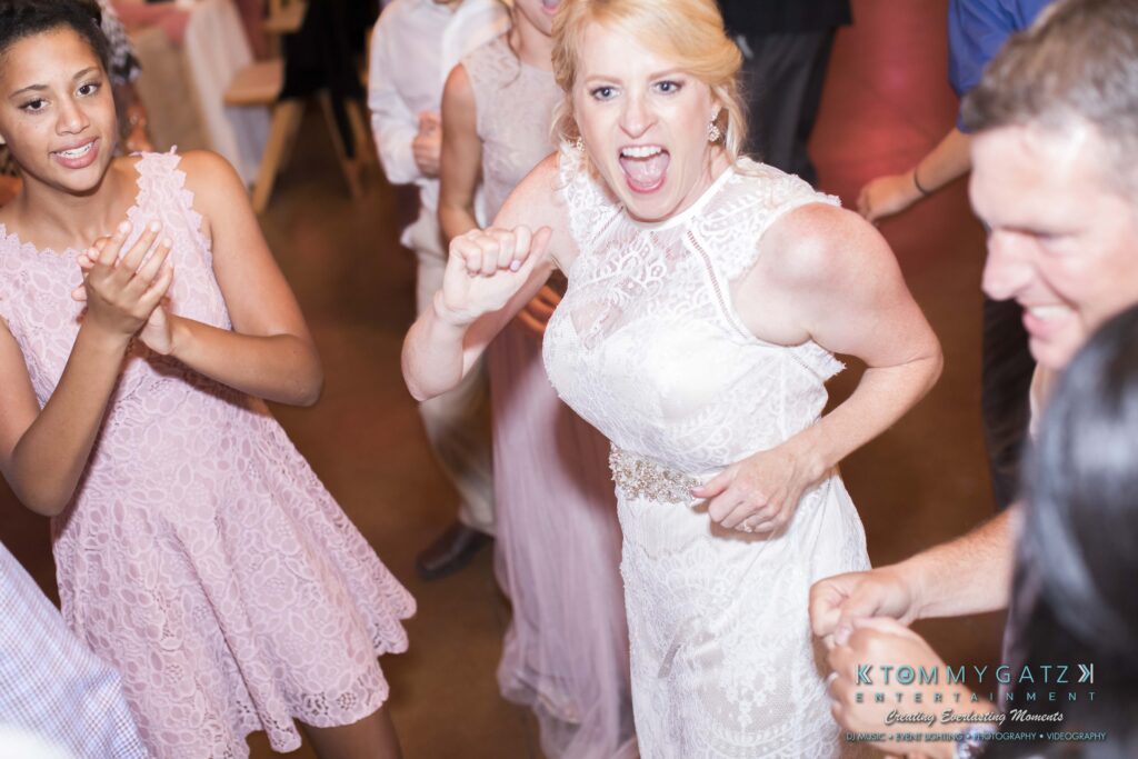 Bride dancing energetically with guests at a wedding reception.