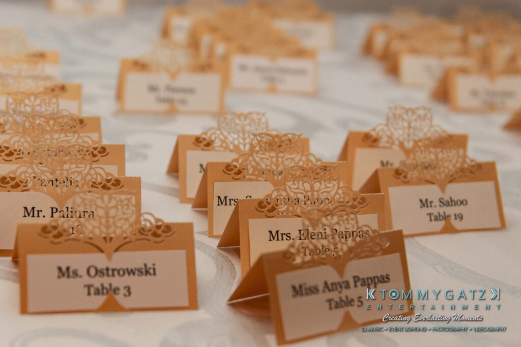 Close-up of wedding name cards arranged on a table, displaying guests' names and table numbers.